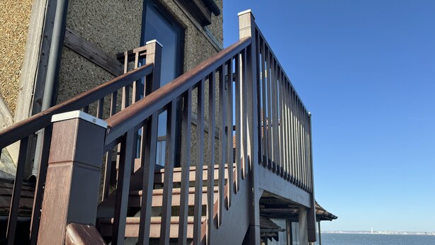 Een houten trap die leidt naar een balkon met uitzicht op het water.