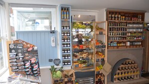 Een winkelinterieur met productstellingen, een krantenstand en een wijnrek.