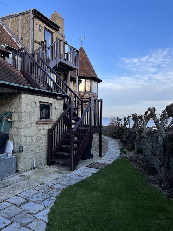 Un edificio de piedra con una escalera de madera que lleva a un balcón con vista al mar.