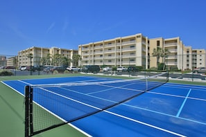 A tennis court with a net, surrounded by a fence, and adjacent to a multi-story building with balconies. - Beautiful 2/2 Direct Oceanfront Condo with Ocean View - Unit 505 Top floor (New Smyrna Beach)