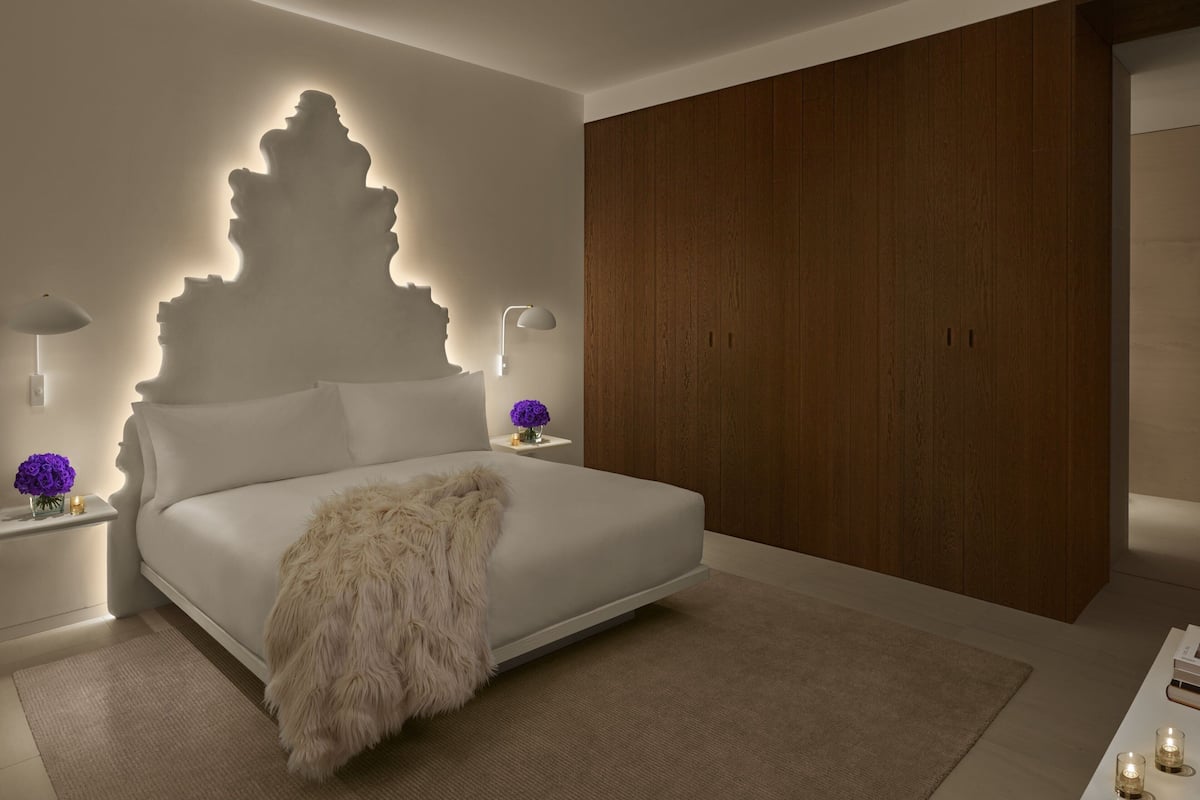 A modern bedroom with a large bed, wooden wardrobe, and bedside lamps.