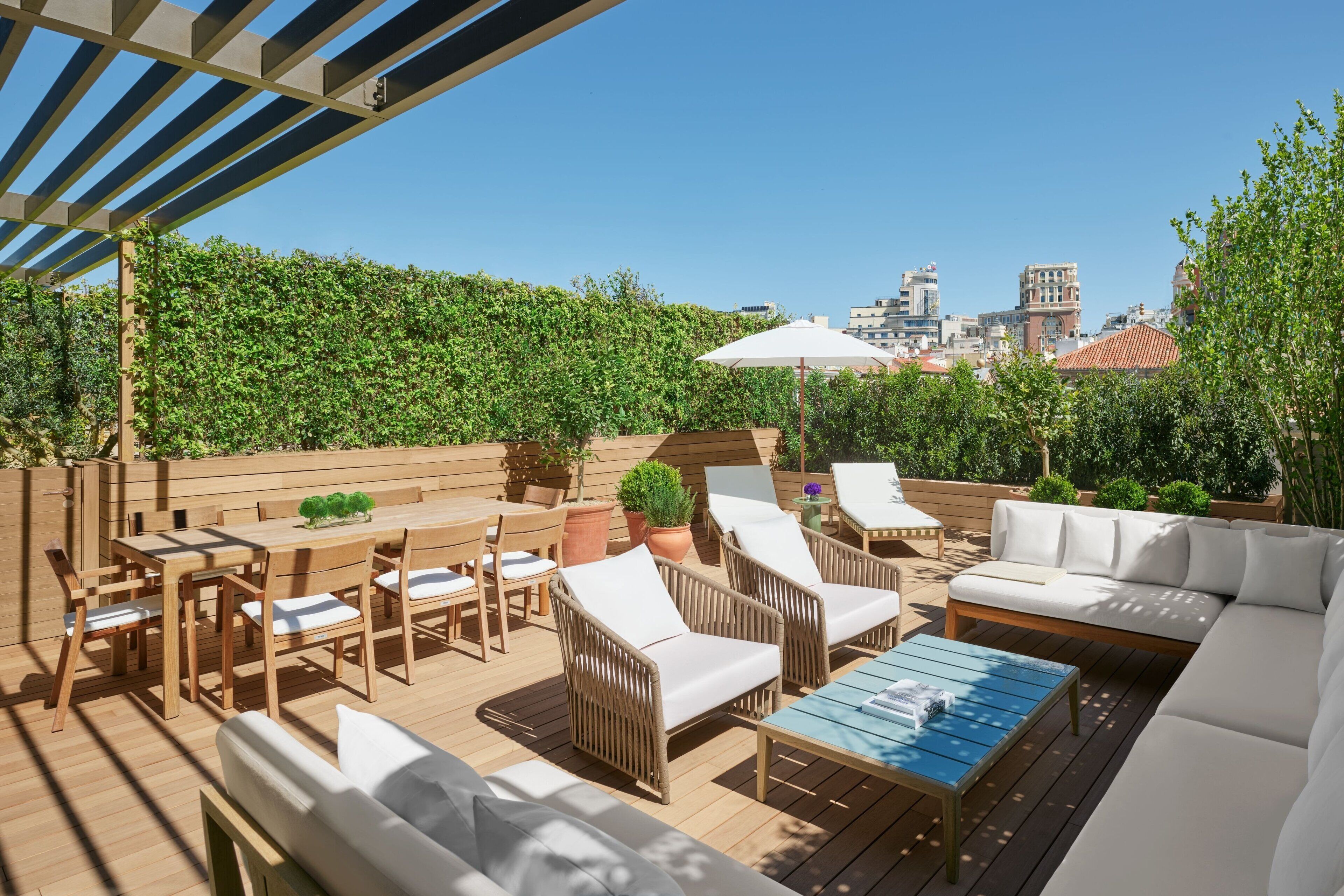 An outdoor patio with wooden furniture, a blue table, and a white umbrella.