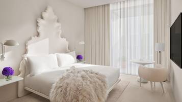 A modern hotel room with a large bed, a fluffy rug, a round table with chairs, and a TV mounted on the wall.