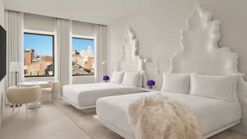 Ein modernes Hotelzimmer mit zwei Betten, einer kleinen Sitzecke und Blick auf die Stadt.