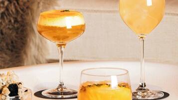 Una mesa con tres vasos de una bebida amarilla, un recipiente pequeño y un posavasos con una etiqueta de nombre.