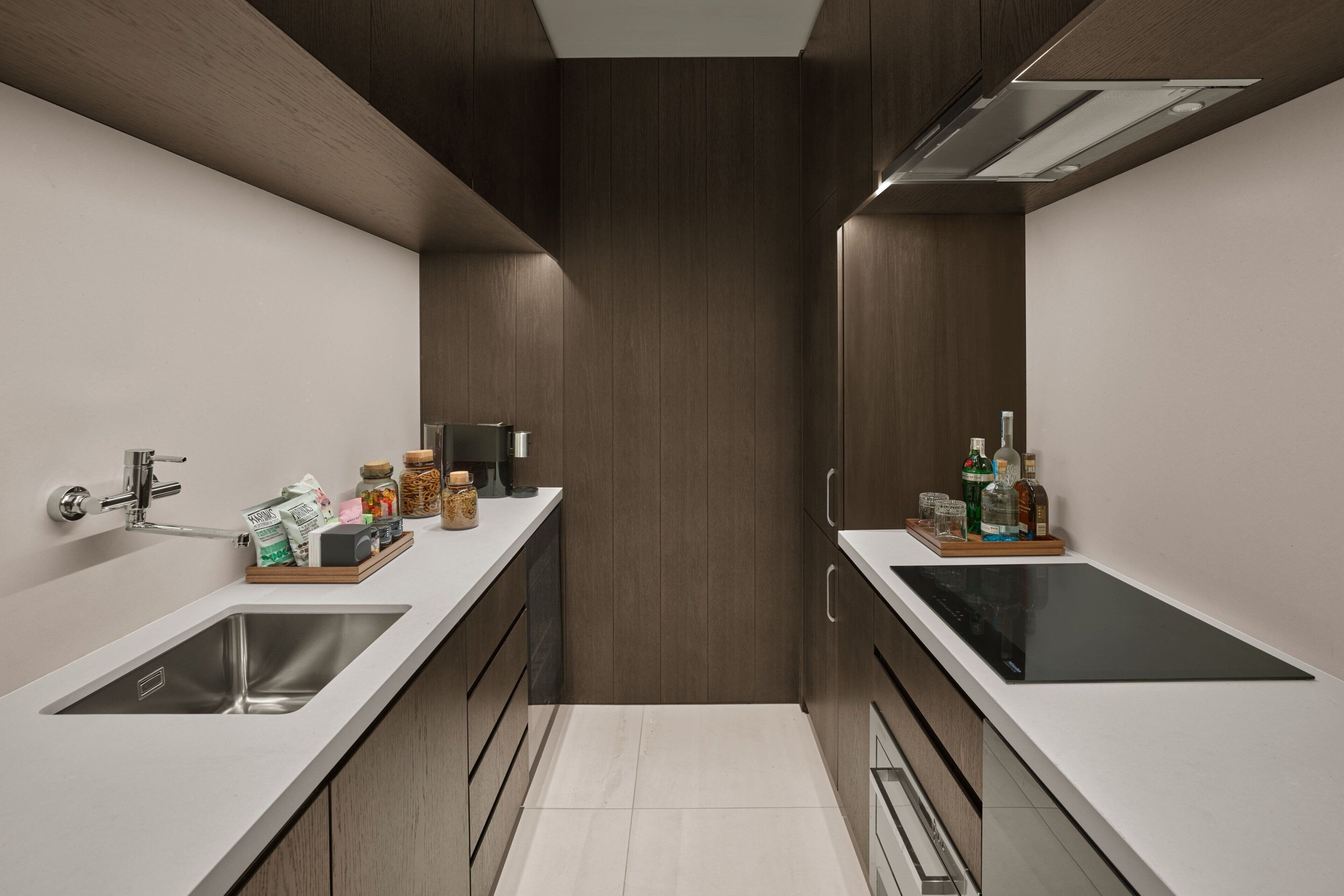 Una cocina moderna con dos fregaderos, armarios de madera y una encimera con diversos objetos.