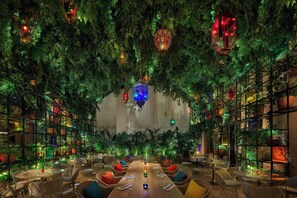A restaurant with a long table in the center, surrounded by chairs, and walls covered with plants. - The Madrid EDITION (Madrid)