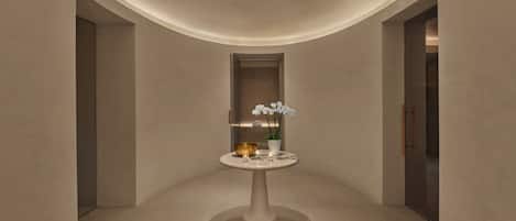 A minimalist interior with a central table, a plant, and a door.
