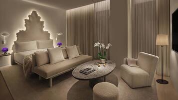 Une chambre d’hôtel moderne, dotée d’un canapé, d’une table basse, d’un fauteuil et d’un lit avec une tête de lit originale.