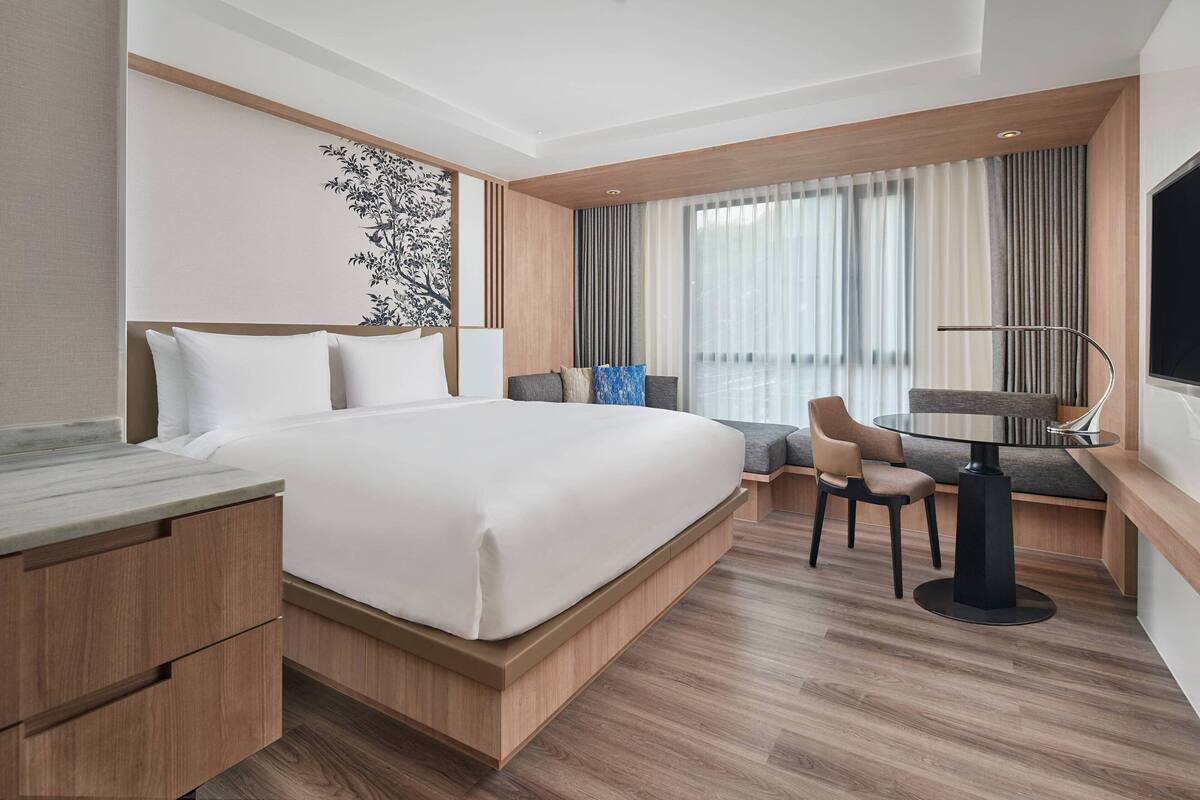 Une chambre d’hôtel moderne avec un grand lit, un bureau avec une chaise et un téléviseur.