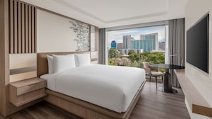 Ein modernes Hotelzimmer mit einem großen Bett, einem Schreibtisch und Blick auf die Stadt.