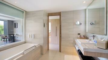 A modern bathroom with a large bathtub, two sinks, a mirror, and a view of a balcony.