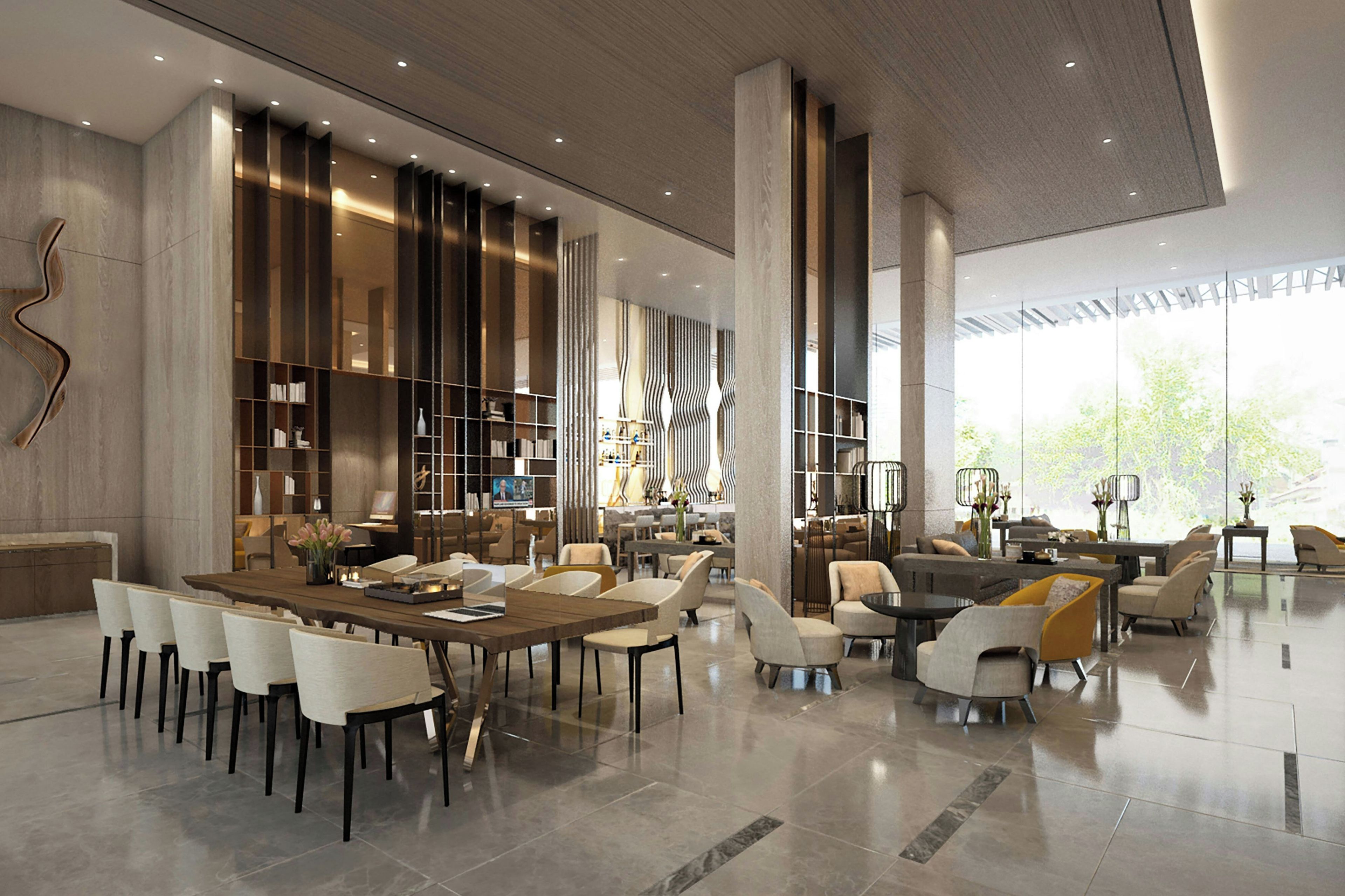A spacious, modern lounge area with high ceilings, large windows, and a variety of seating arrangements including tables and chairs.