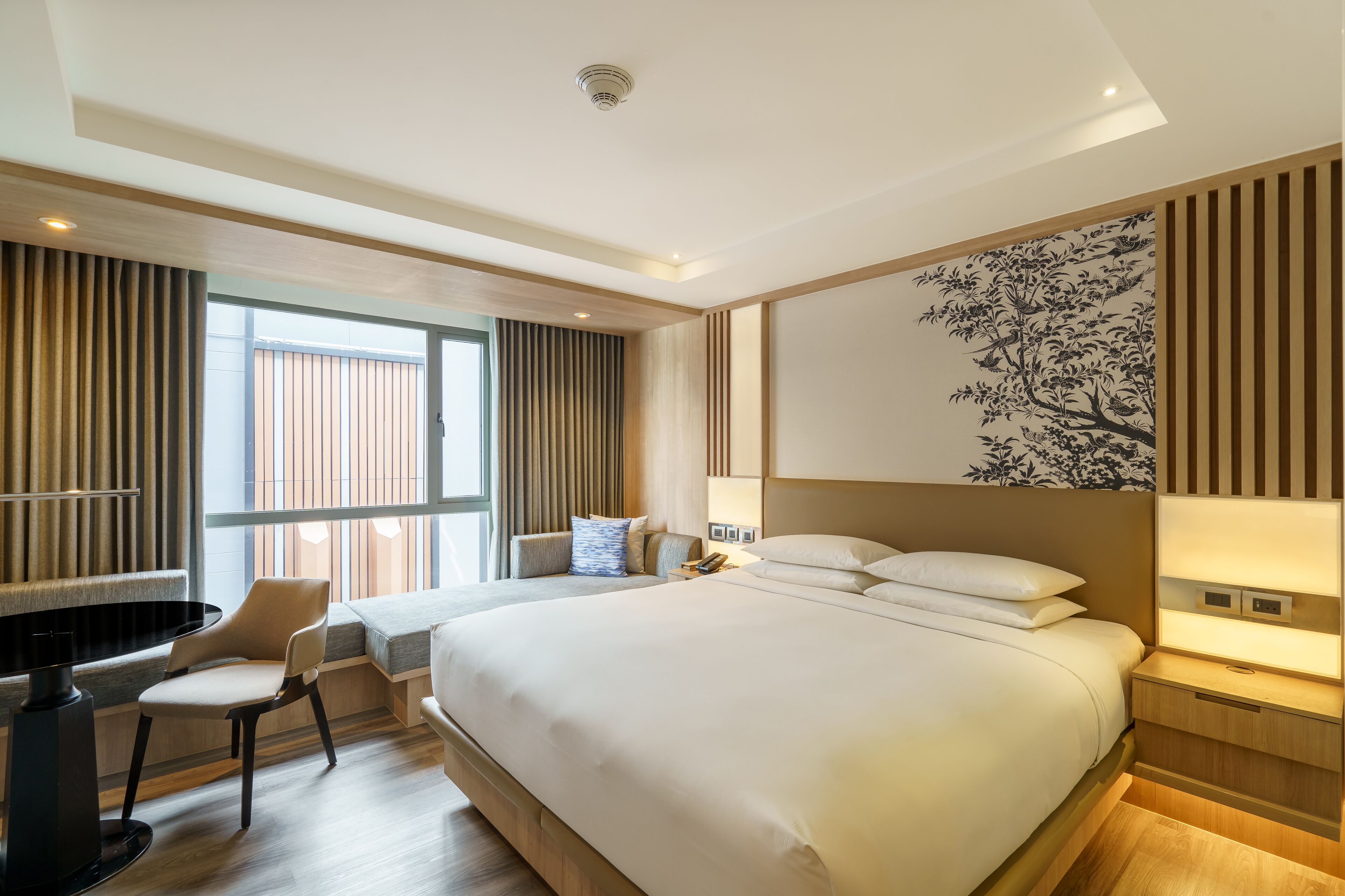 A modern hotel room with a large bed, a desk, and a chair.