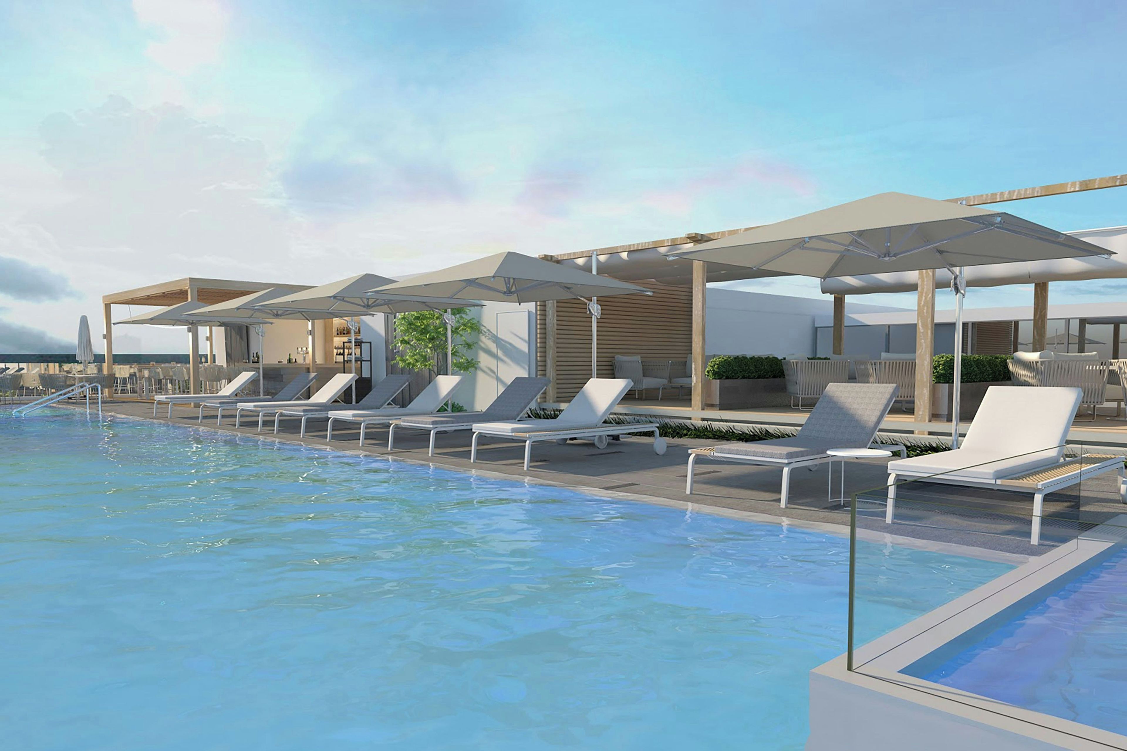 A swimming pool with lounge chairs and umbrellas, a bar area, and a view of the sky.