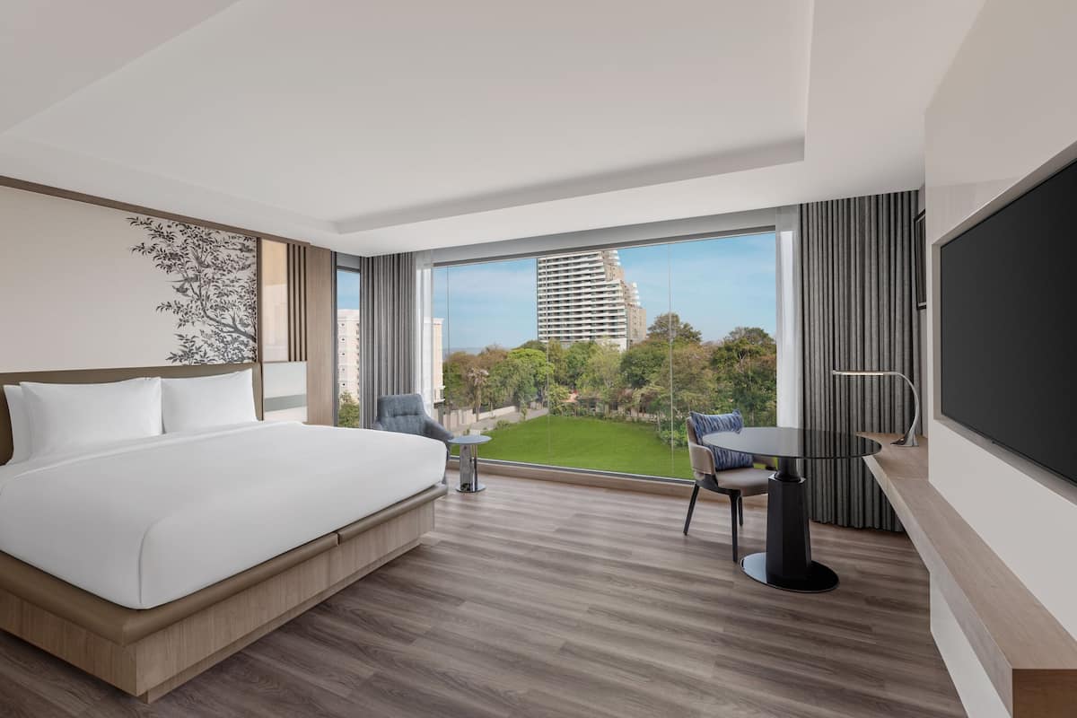 Une chambre d’hôtel moderne avec un grand lit, une petite table, une chaise et un téléviseur.