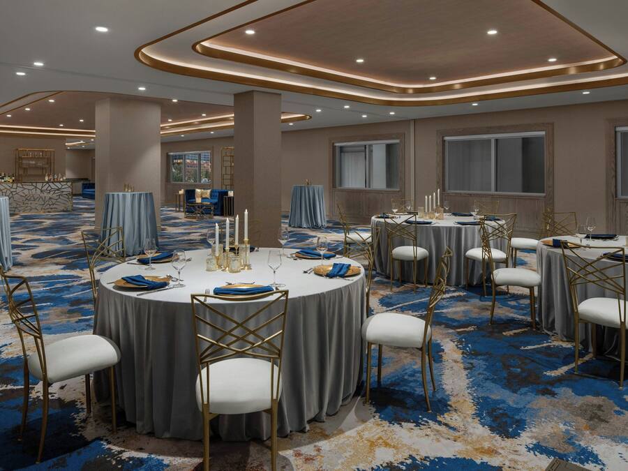 A conference room with round tables, white chairs, and a blue carpet.