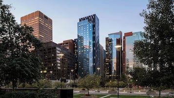 A cityscape with modern high-rise buildings, a park area with benches, and a clear sky.