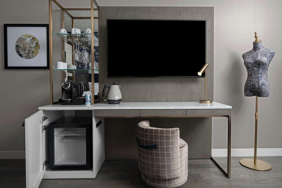 Una cocina moderna con un refrigerador empotrado, una encimera blanca y un televisor de pantalla plana grande montado sobre la encimera.