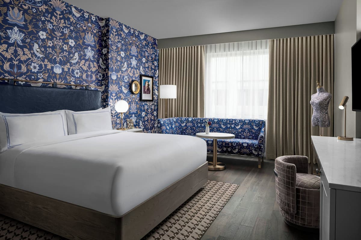 Habitación de hotel con una cama grande, una mesa redonda, un sofá y un escritorio con una lámpara.