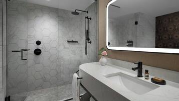 Un baño moderno con ducha de azulejos hexagonales, un espejo grande y un lavabo de mármol.