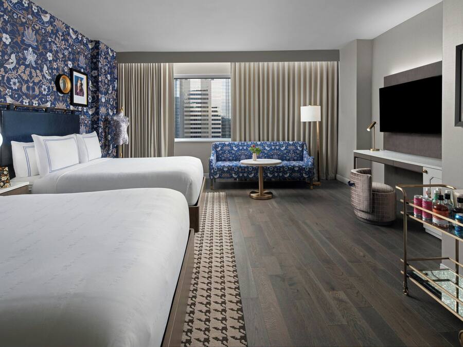 Una habitación de hotel con dos camas, un sofá, un televisor y un minibar.
