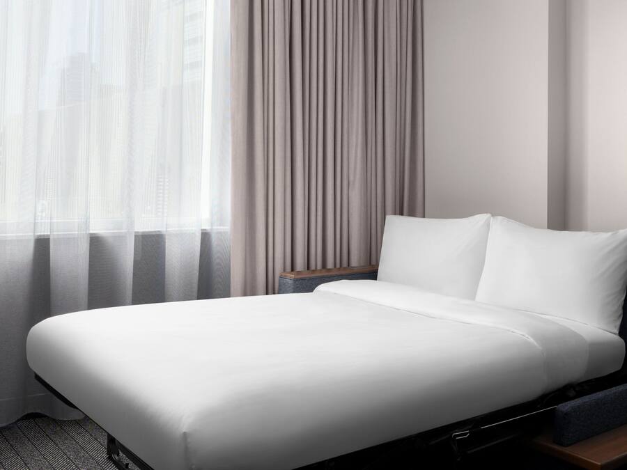 Una cama bien hecha con sábanas blancas en una habitación de hotel.
