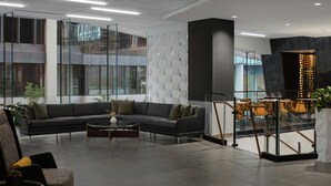 Een moderne lobby met een modulaire bank, een bijzettafeltje en een trap naar een hoger gelegen verdieping.