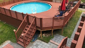 A circular hot tub with a wooden deck and a small staircase leading down to the pool.