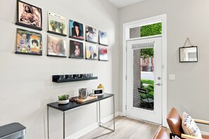 A room with a door leading to a balcony, a console table with a plant, and a wall with framed pictures. - 1st Floor & No Steps, close to Vanderbilt, Belmont & Food (Nashville)
