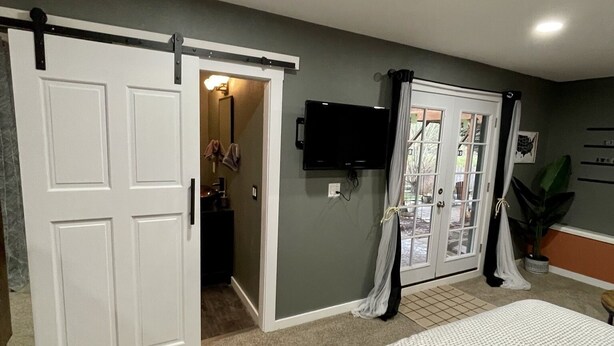 A bedroom with a bed, a sliding door, a television, and a plant. - Private getaway in a beautiful neighborhood (Salem)