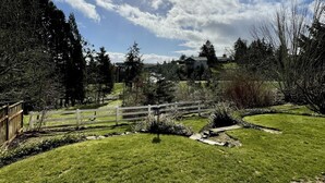 A grassy outdoor area with a wooden fence, a stone pathway, and trees in the background. - Private getaway in a beautiful neighborhood (Salem)