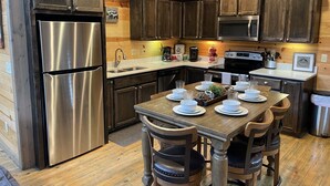 Una cocina con armarios de madera, electrodomésticos de acero inoxidable y una mesa de comedor para cuatro personas.