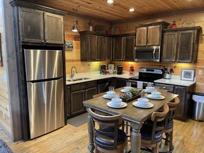 Une cuisine dotée de meubles en bois, d’appareils électroménagers en acier inoxydable et d’une table à manger pour quatre personnes.
