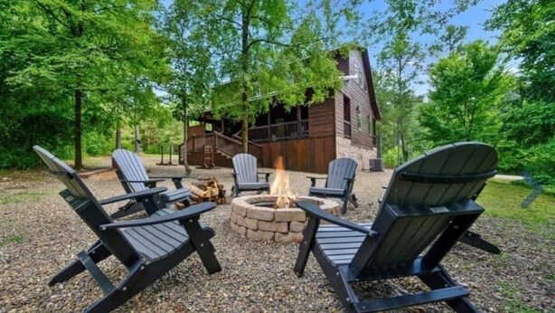 Una cabaña con una fogata rodeada de sillas Adirondack.