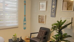 A living room with a dark wicker sofa, a small side table, a potted plant, and framed artwork on the wall. - Playa icacos (Fajardo)