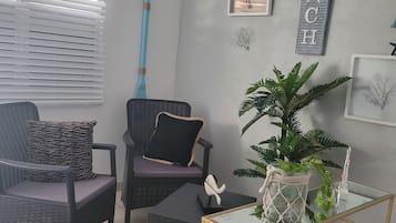 A living room with a sofa, armchair, coffee table, and a small side table with a plant.