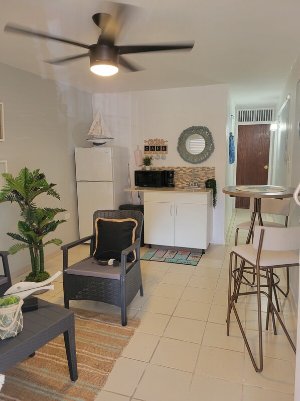 A compact living space with a kitchenette, a ceiling fan, a small dining area, and a seating arrangement. - Playa icacos (Fajardo)