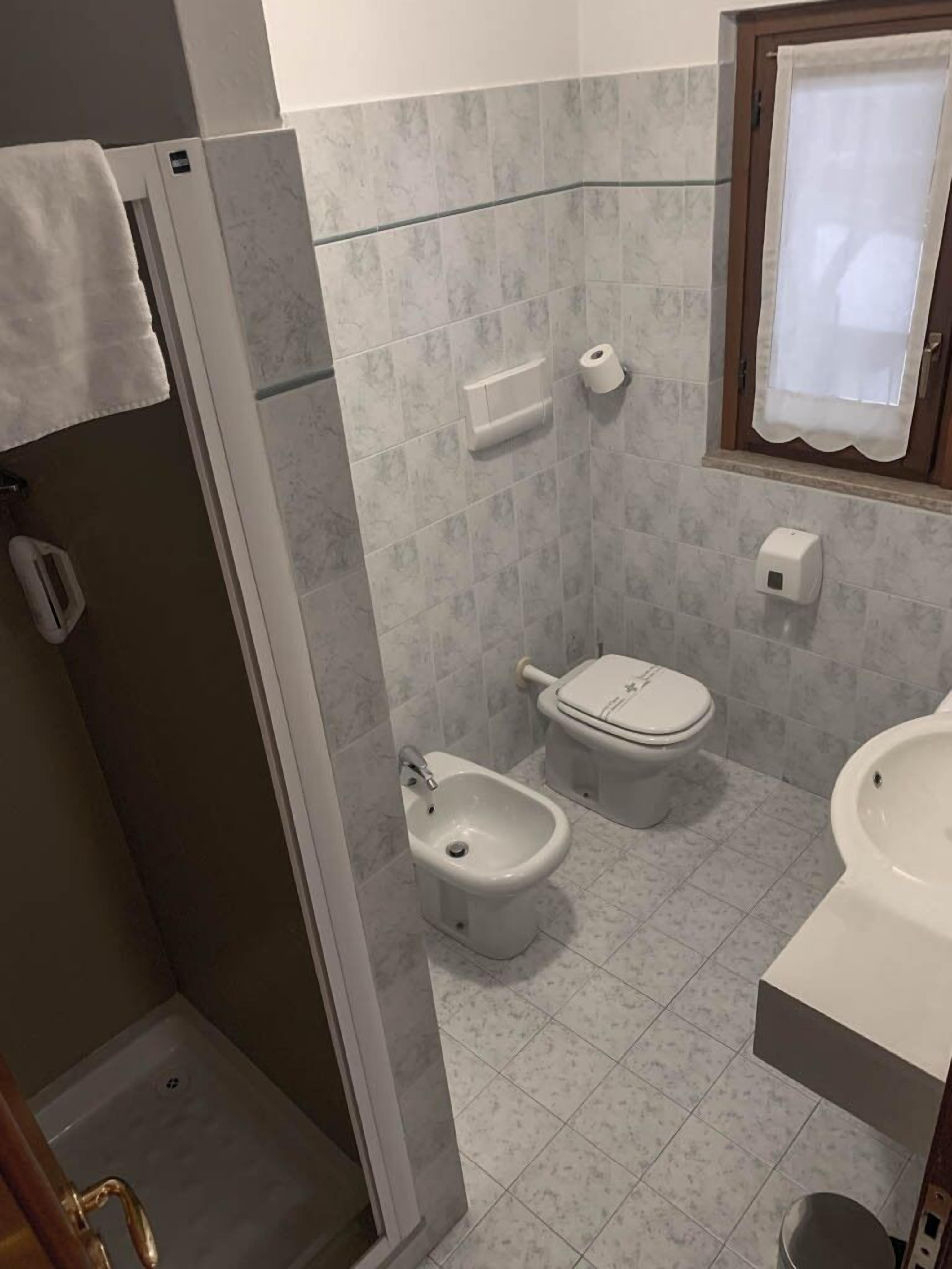 Une salle de bain équipée d’une douche, de toilettes, d’un bidet et d’un lavabo.