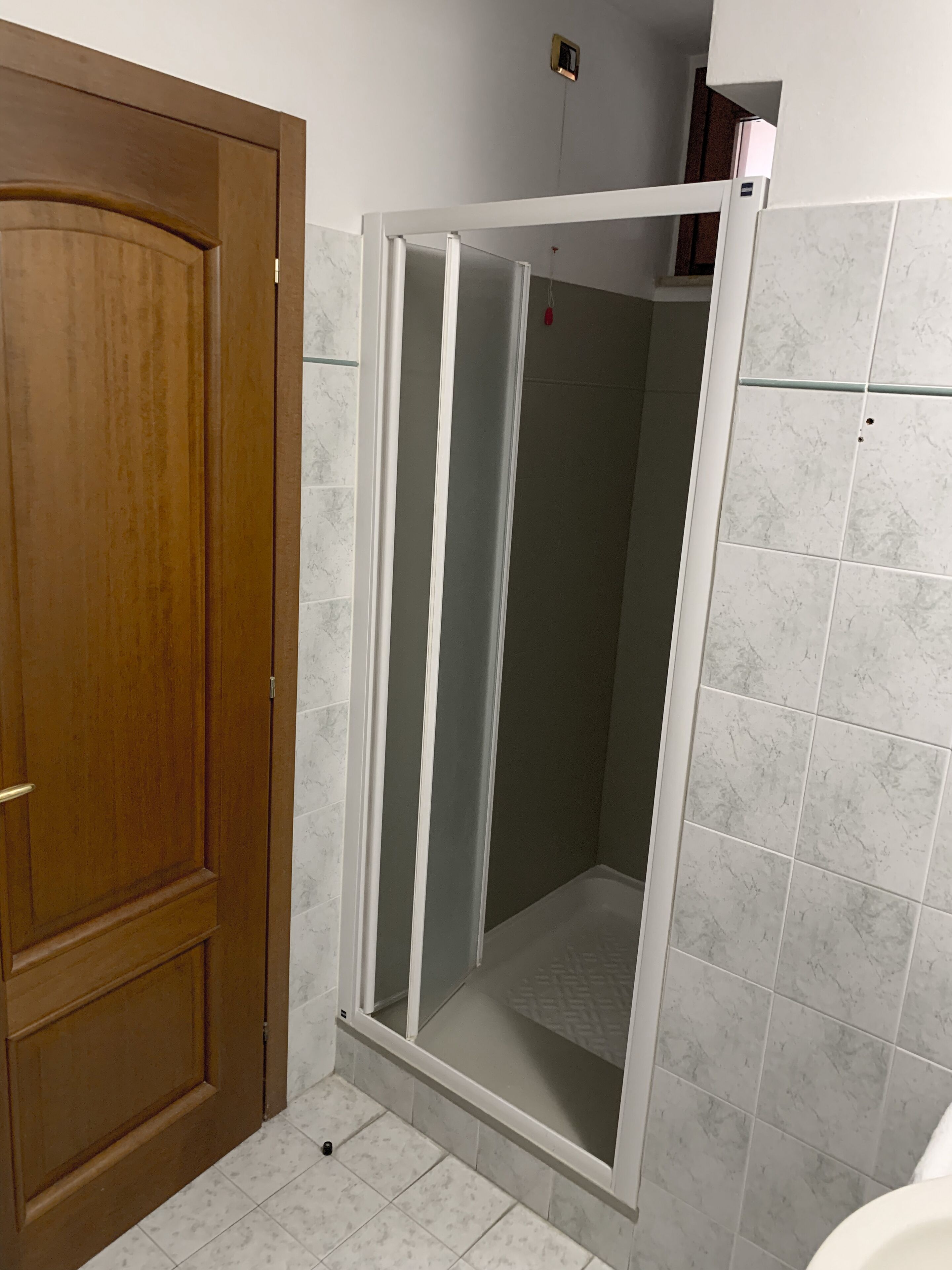 Un baño con puerta de madera, cabina de ducha y paredes de azulejos.