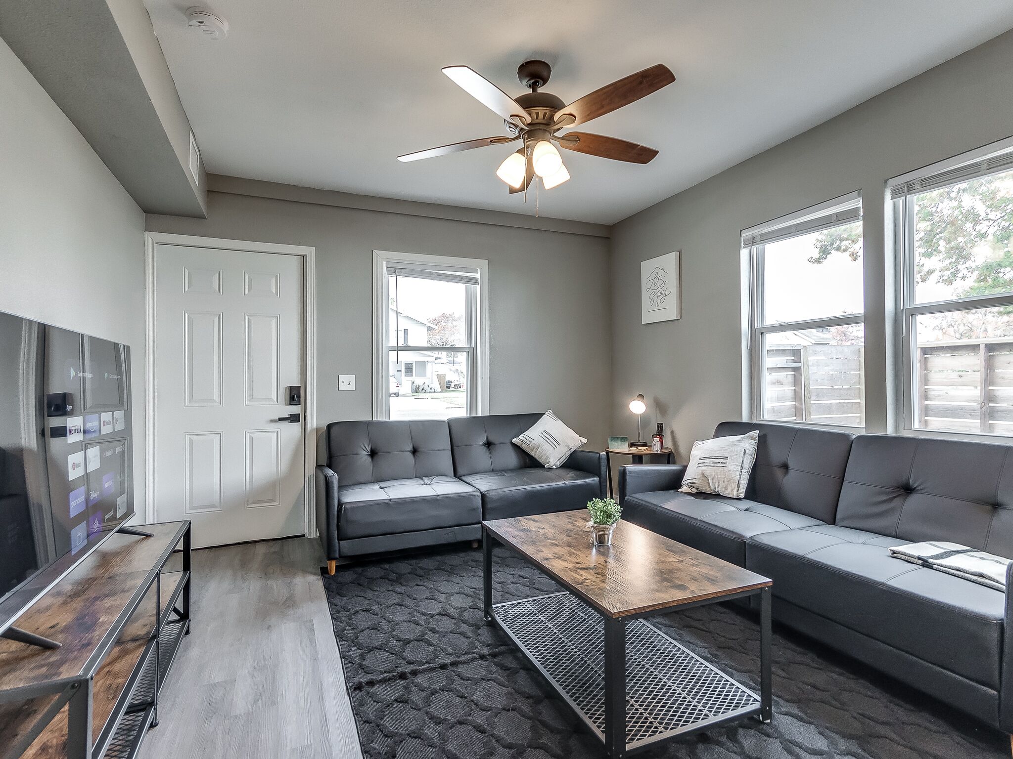 A modern living room with a sofa, a coffee table, a TV, and a ceiling fan.