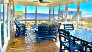 A covered outdoor seating area with a view of the ocean, wooden furniture, and a ceiling fan. - 5 Bedroom Beach House Slps 12 - Private Beach - Shells - Fishing -Screened porch (Panacea)