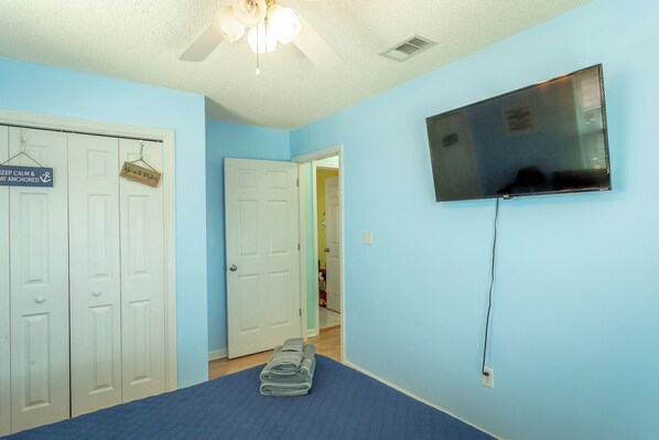 A bedroom with a bed, a ceiling fan, a TV mounted on the wall, and a door with a sign. - 5 Bedroom Beach House Slps 12 - Private Beach - Shells - Fishing -Screened porch (Panacea)