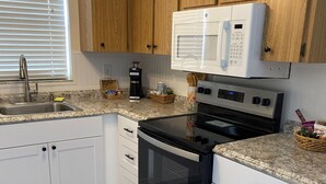 A kitchen with white cabinets, a stainless steel oven, a microwave, and a coffee maker.