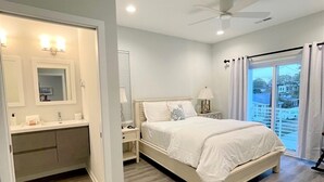 A bedroom with a bed, a nightstand, a dresser, a ceiling fan, and a view of the outside. - Modern Beach Home with Golf Cart! Dog Friendly! (Carolina Beach)