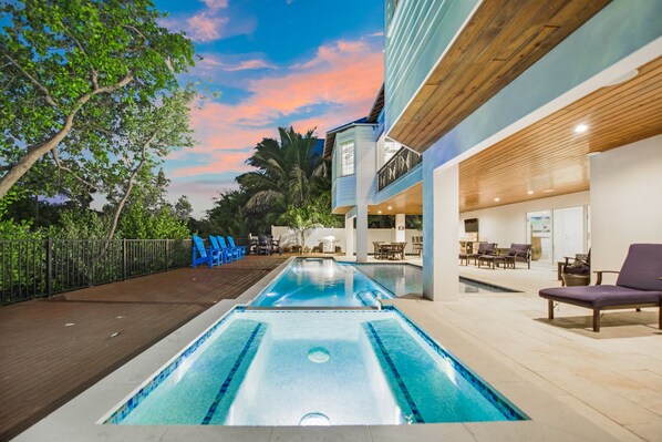 Un espace piscine doté d’une terrasse en bois, de chaises longues et d’un bâtiment au plafond en bois.