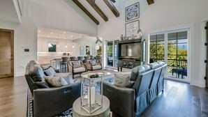 A spacious living room with a large sectional sofa, a fireplace, and a television. - Tern Key - Luxury Canal-Front Home w/ Heated Pool, Spa, Dock & Near Bean Point (Anna Maria)