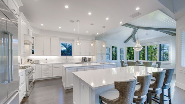 A spacious kitchen with white cabinetry, a large island, and pendant lighting. - Tern Key - Luxury Canal-Front Home w/ Heated Pool, Spa, Dock & Near Bean Point (Anna Maria)