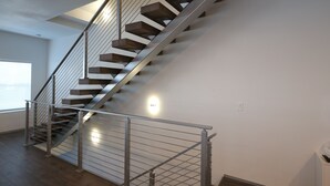 A modern staircase with metal railings and wooden steps, leading to an upper floor. - Modern Home With Rooftop Patio - Down Town Views (San Antonio)