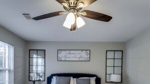 A bedroom with a bed, a ceiling fan, a bedside table, a lamp, and a wall decoration. - *Modern oasis 7 mins from Atlanta airport (College Park)